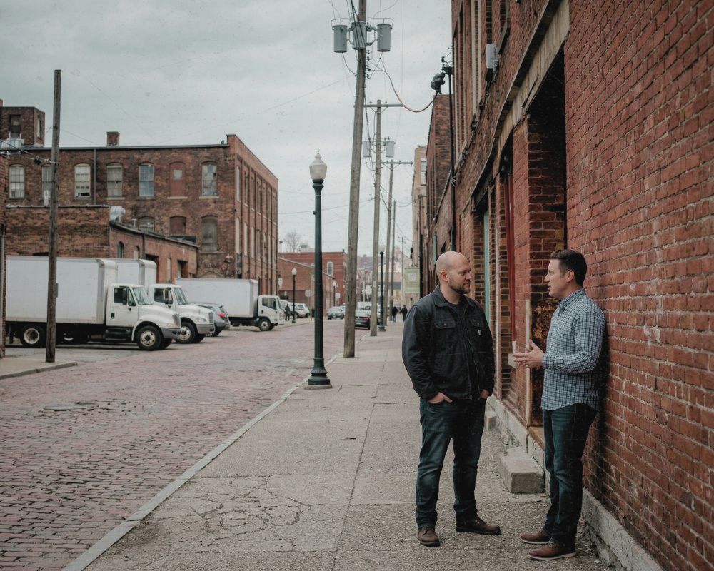 Two members of WNY Operators Group in conversation on a cobblestone street
